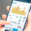 Smartphone med energiovervågning fra Aquarea Smart Cloud, viser strømforbrug og grafer i app-interface.
